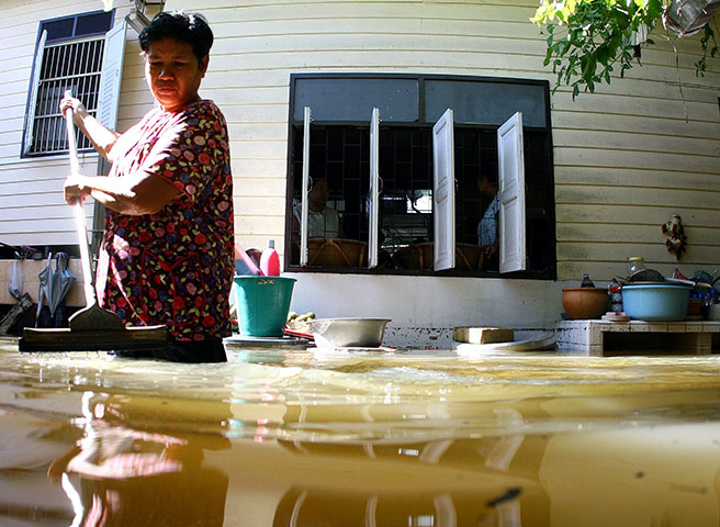 24 hours: Bangkok, Thailand: A Thai woman sweeps debris at  her flooded house