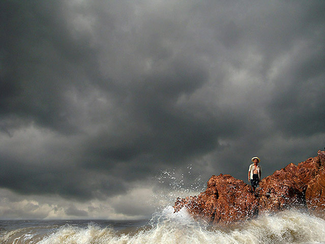 24 hours: Zhangpu, China: A man watches as waves crash into rocks in Fujian province