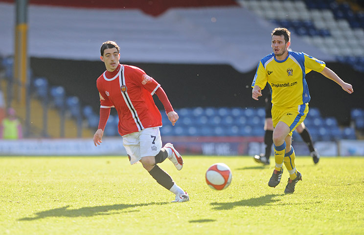FC United: Carlos Roca of FC United is chased by Simon Spender of Barrow AFC