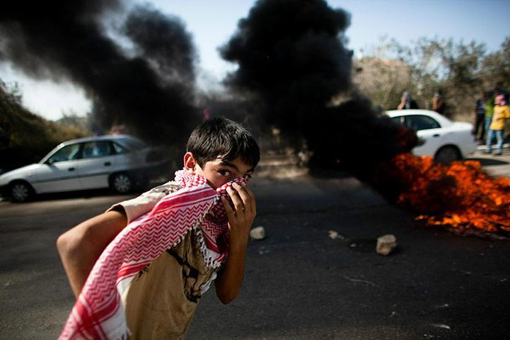 Israel Protest: An Israeli Arab boy passes by a fire during clashes in Umm el-Fahm