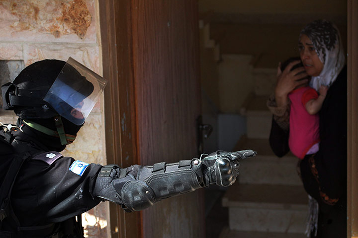 Israel Protest: An Israeli riot policeman tells a woman holding her child to leave her home