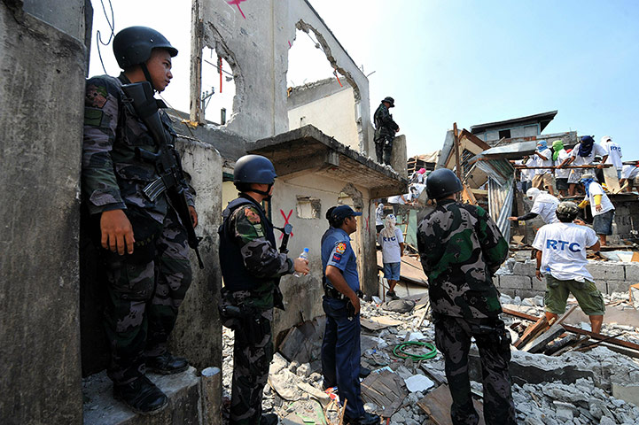 24 Hours In Pictures: Policemen stand in the middle of a demolition in Manila