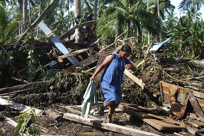 Indonesia update: A woman collects clothes from the debris of her  tsunami hit home