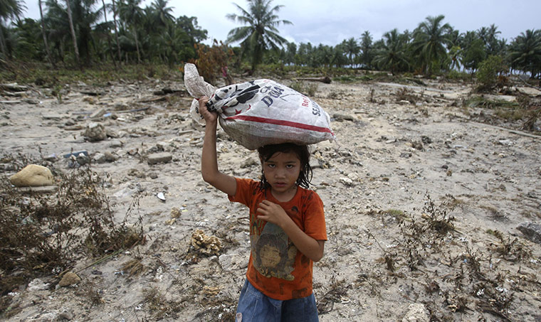 indonesia tsunami: A young Tsunami survivor carries her belongings