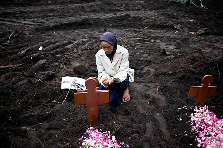 24 hours in pics: A woman prays at a burial of a victim of the Mount Merapi eruption