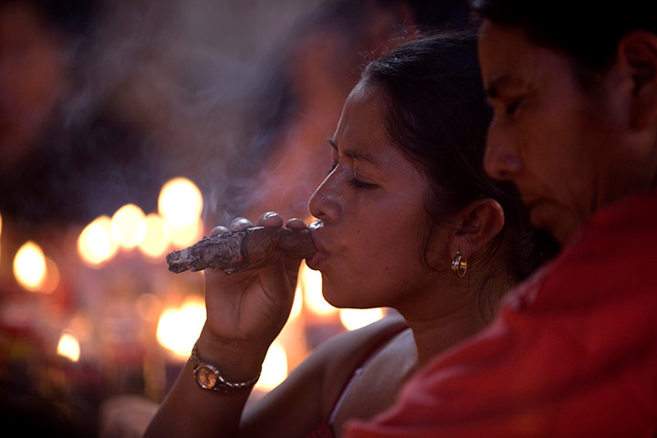 24 hours in pics: A woman smokes a cigar during the celebrations of Maximon