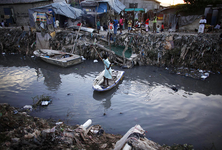 24 hours in pictures: A resident crosses a dirty drain, downtown Port-au-Prince