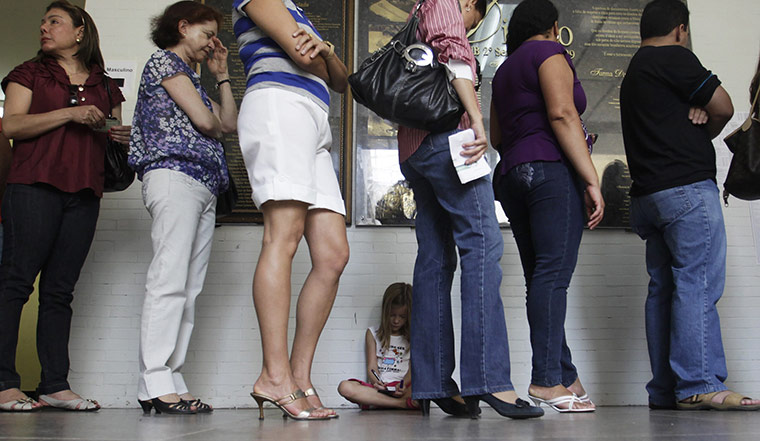 Brazil elections: A girl sits as people wait in line to vote at a polling station 