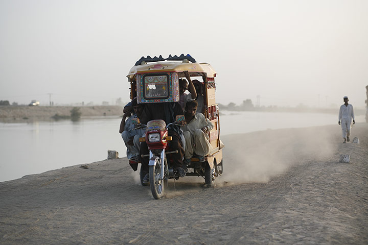 Sehwan Sharif Pakistan: A rickshaw travels along a canal embankment in Sehwan Sharif