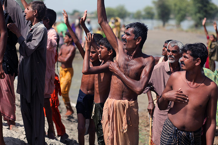Sehwan Sharif Pakistan: Villagers wave to a Pakistani army helicopter dropping food aid 
