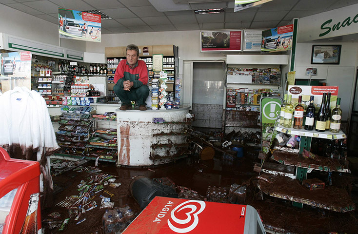 Hungary sludge flood: A shopkeeper squats on the counter of a flooded petrol station