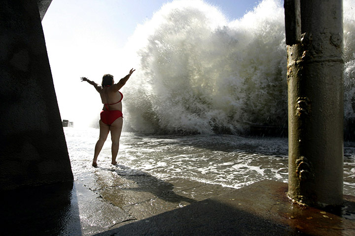 24 hours in pictures: A woman stands in front of a large wave on the beach of the Black sea