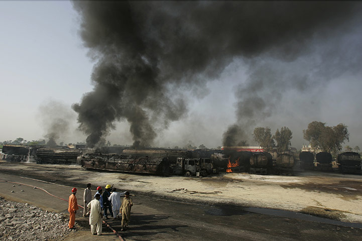 Pakistan tankers attack: 1 October: Pakistani firemen stand beside oil trucks in Shikarpur