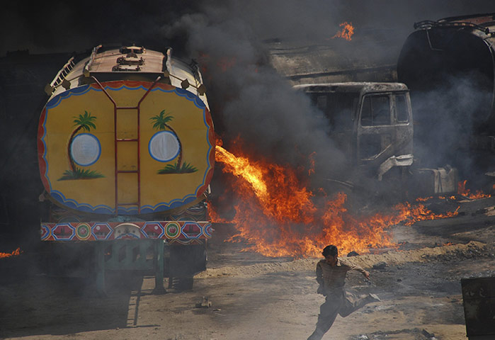 Pakistan tankers attack: 1 October: A man runs away from burning oil tankers