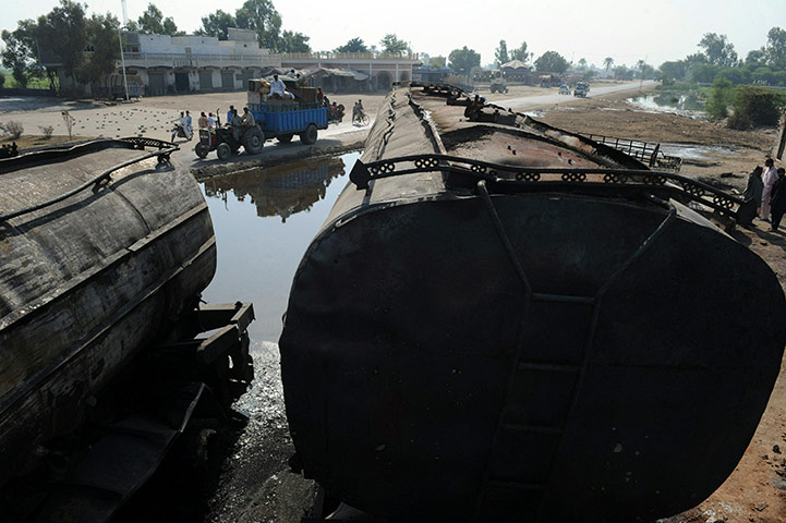 Pakistan tankers attack: 1 October: Pakistani people ride past burnt out NATO supply trucks