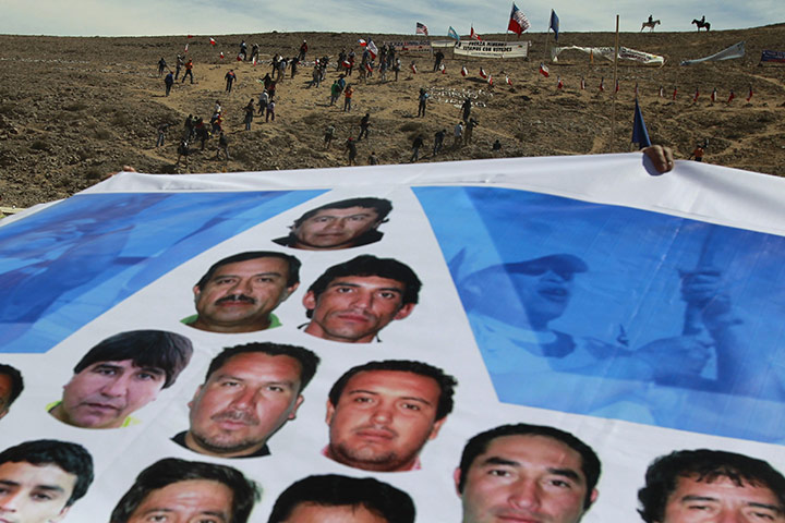 Chile miners rescue: 5 October: Relatives of the 33 miners hold a flag printed with portraits