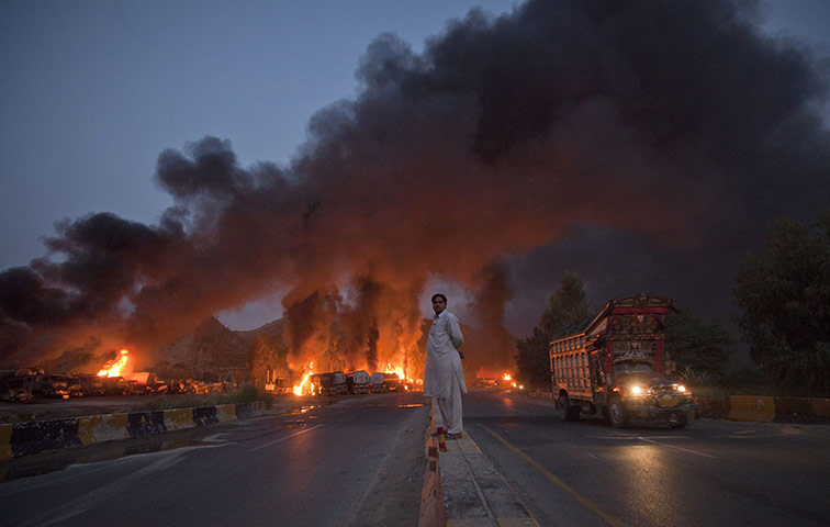 NATO Tankers Pakistan: 6 October: A local resident watches fuel tankers burn in Nowshera