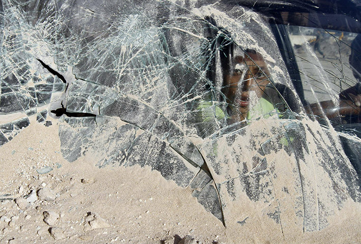 24 hours in pictures: A young boy looks through broken glass at a military site, Gaza city