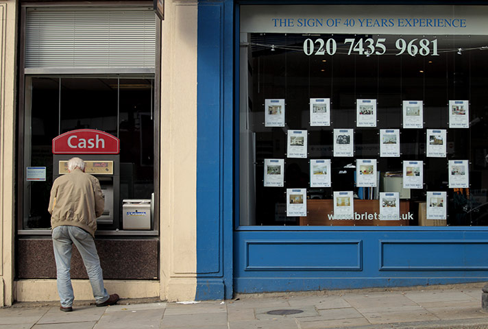 Week in Business: A man uses a cash machine next to an estate agents in Hampstead
