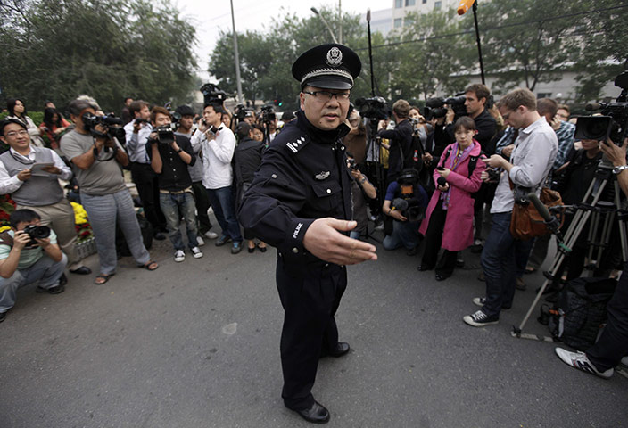 Liu Xiaobo Nobel Peace: A policeman gestures to reporters at the residence of Liu Xia