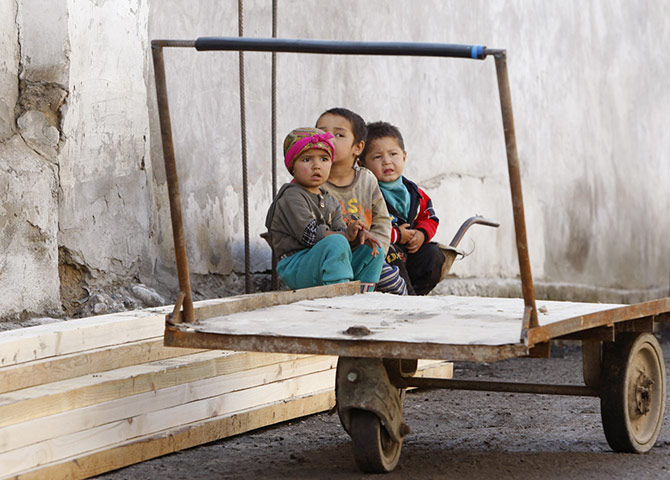 24 hours in pictures: Ethnic Uzbek children sit at their destroyed house in Osh