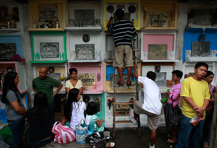 All saints day: A Filipino man places candles on the tomb of a relative at cemetery