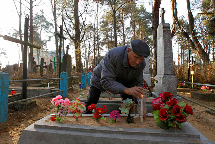 All saints day: Man lights candle on a grave at a cemetery in the village of Ivenets