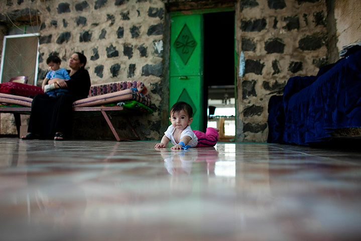 24 hours in pictures: A baby crawls on the ground outside her house in the village of Ghajar
