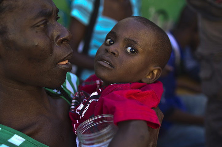 Cholera in Haiti: A woman carries a child with symptoms of cholera in Port-au-Prince