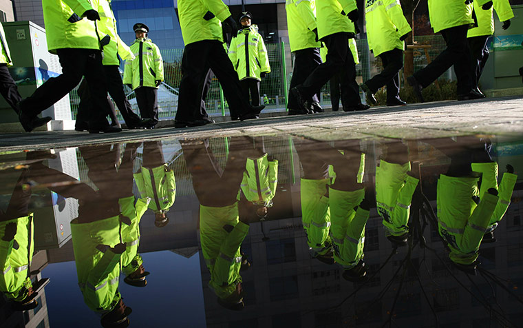G20 Summit Update: Policemen are reflected in a puddle as they march around the secure area