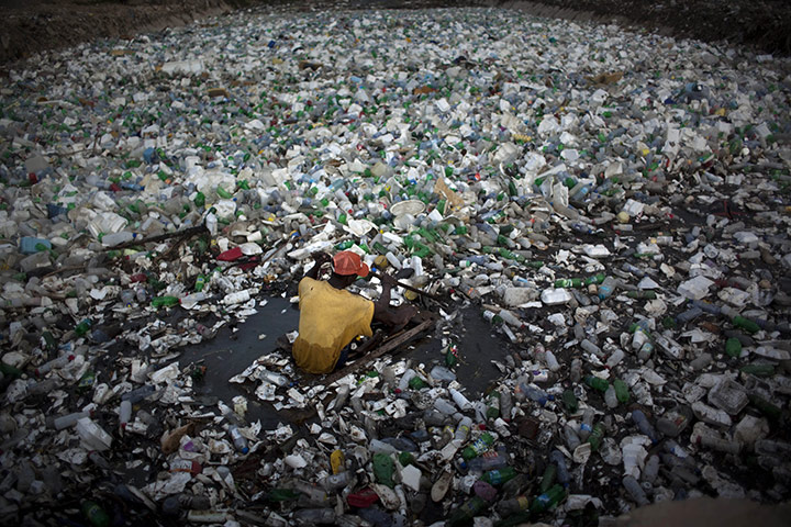 24 Hours: A Haitian man collects garbage through a river of waste