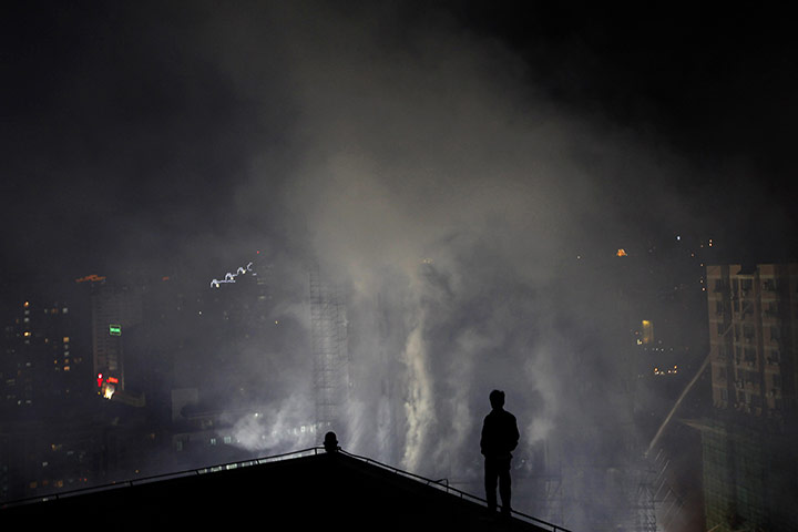 24 hours in pictures: A resident watches a burning building in Shanghai