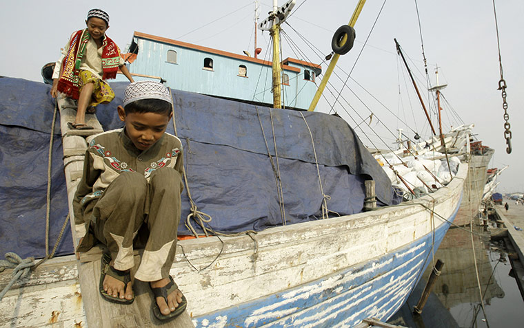 Eid al-Adha: Indonesian Muslim boys cross over a traditional ship