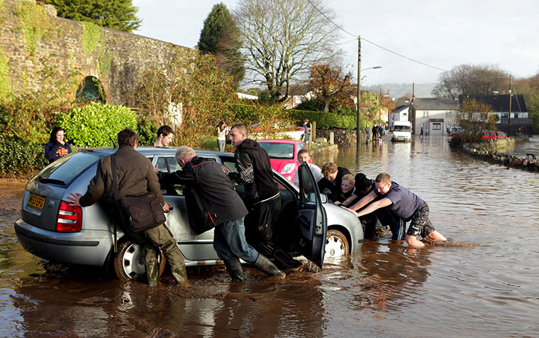 cornwall flooding update: Residents move a car stranded in flood water in St Blazey
