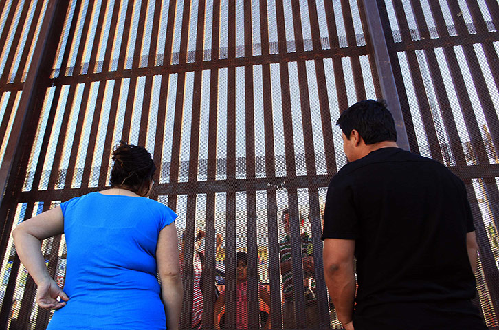 Eric Thayer : Betcy Cruz and Marco Cruz talk with family members at the fence 