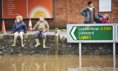 Children sit on a wall above floodwater in St Blazey, Cornwall