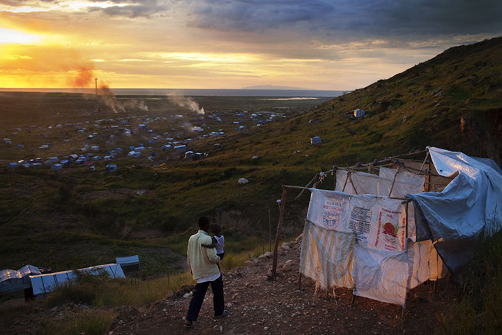 Haiti Cholera Devastation: Emmanuel Tima, 34, and his son Emmaneul, 3 walk through the camp in Haiti