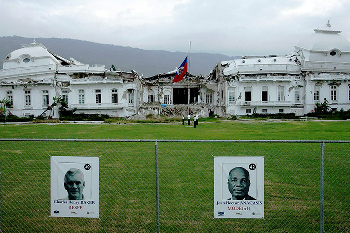Haiti Cholera Devastation: Campaign posters are placed on a fence before the ruins of the Palace 