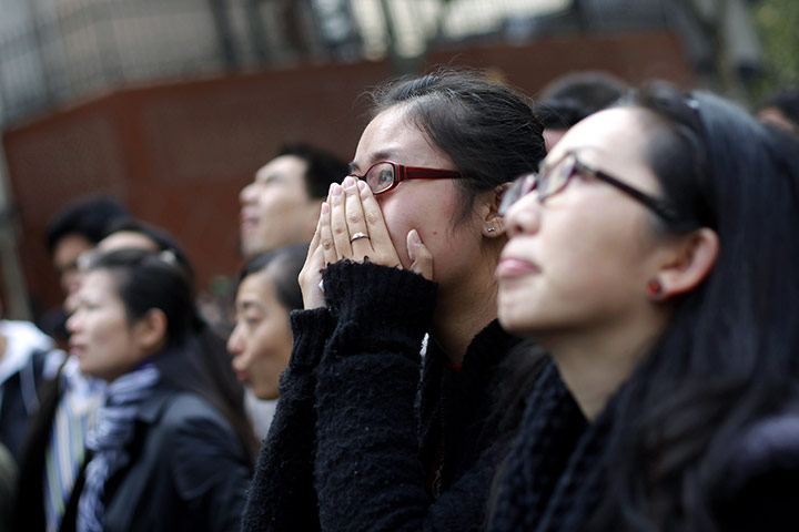 Shanghai Memorial: People react as they look on at the entrance of a burnt apartment block