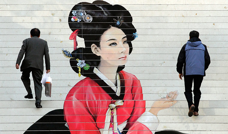 24 hours in pics: Men walk by an advertisement in Seoul, South Korea