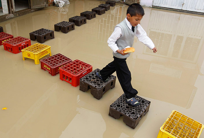 24 hours in pics: A child walks on crates on a flooded street in Bogota