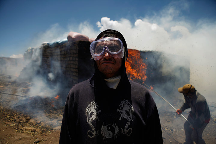 24 hours in pics: A man looks on during the incineration of coca leaves, Bolivia