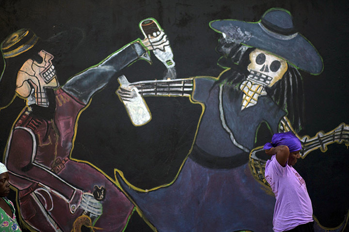 All Saints: Port-au-Prince, Haiti: A woman stands by a mural 