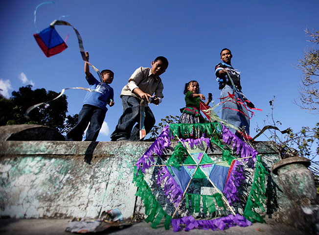 24 hours pics: A family flies kites on top of tombstones during Day of the Dead festival