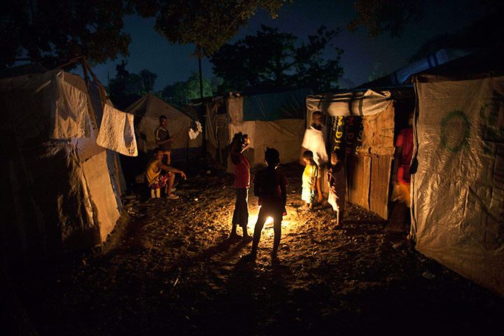 24 hours pics: Earthquake survivors gather around a bonfire at a makeshift camp, Haiti