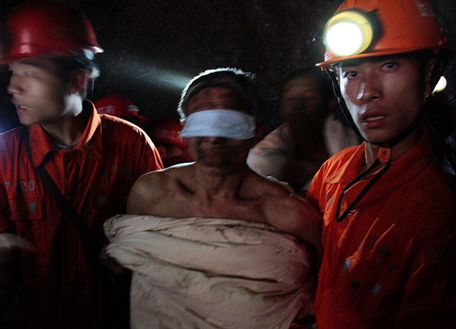 China's trapped miners: Rescuers escort a trapped miner wrapped in white quilt 