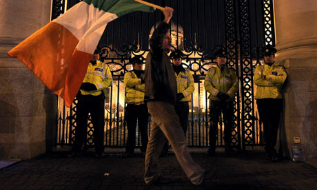 A protester waves a Irish flag outside the Irish Prime Ministers office in Dublin 