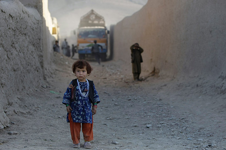 24 hours in pics: An Afghan girl looks at US Army soldiers,  East Now Ruzi village