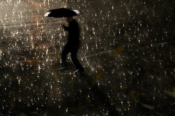 24 hours in pics: A man walks with his umbrella during a heavy rain in Pristina