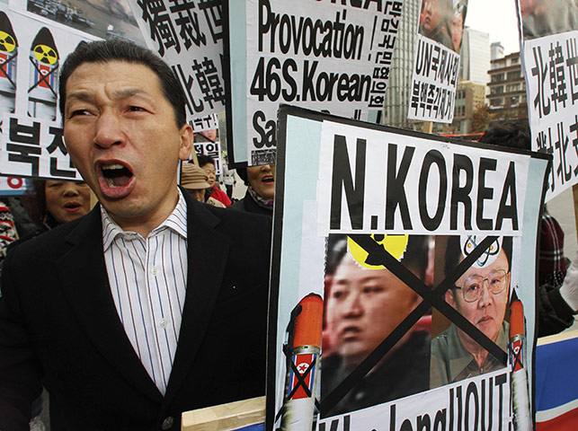 Yeonpyeong island : Protesters shout slogans while holding defaced portraits